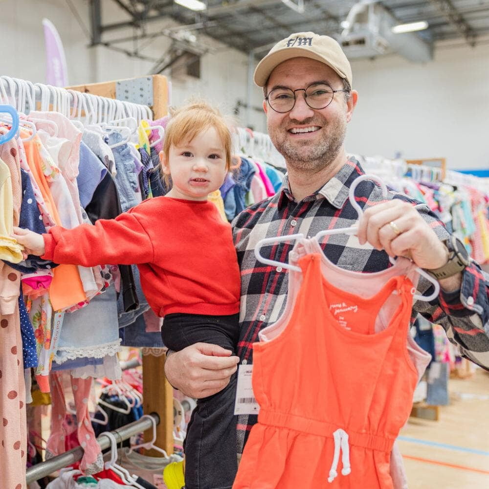 A Dad smiles with his daughter at the JBF Sale