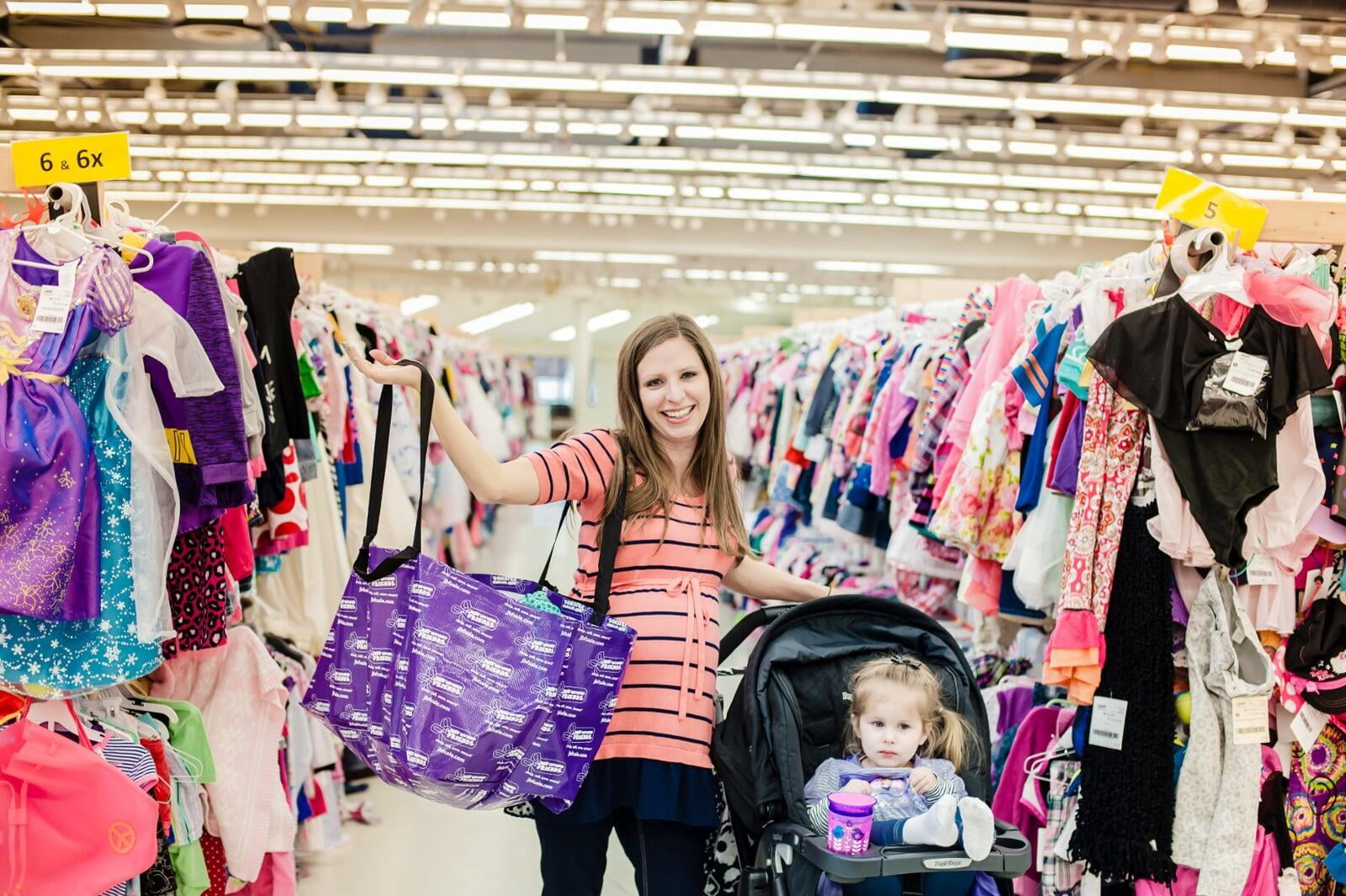 A mom and her JBF Bargains in between two rows of little girl clothes